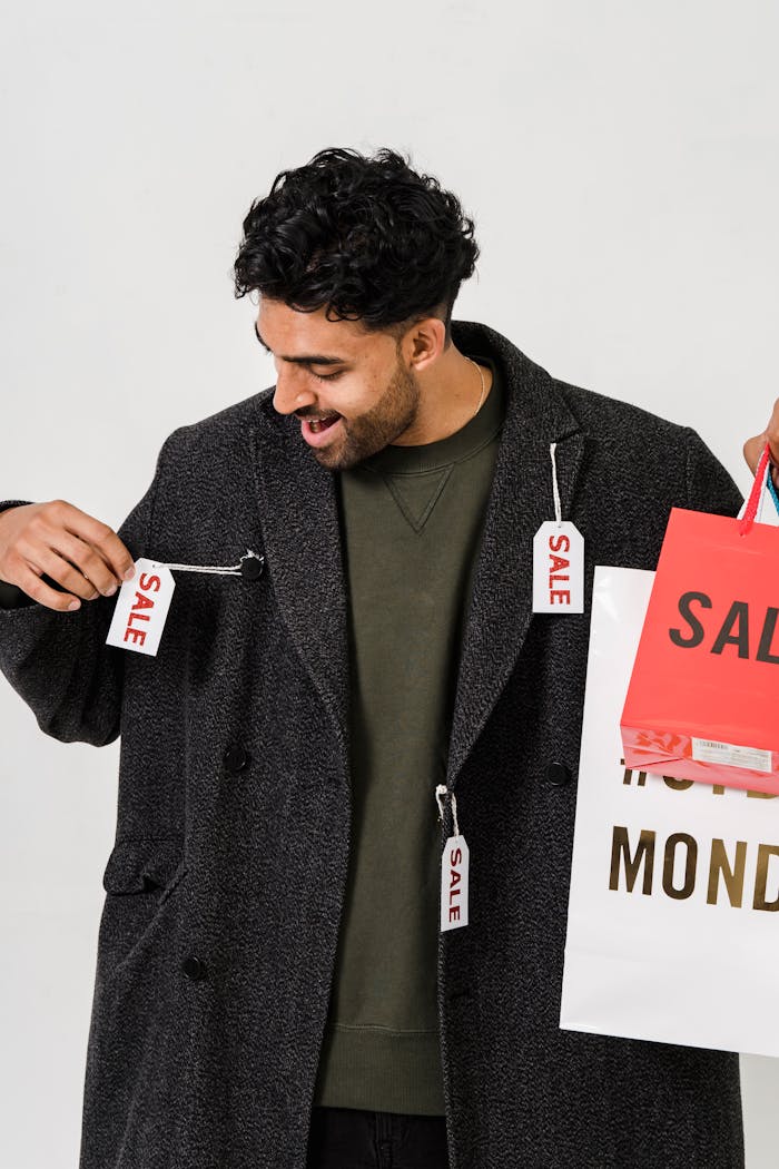 about-us-01 Happy man holding shopping bags with sale tags, signaling retail discounts.